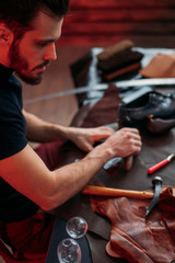 handsome worker of shoemaking industry.close up cropped photo. man cutting material into shape