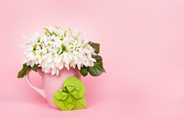 Galanthus on pink background. Bouquet Galanthus. Green paper heart. Heart origami.