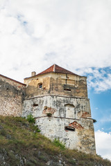 Fototapeta na wymiar Tower of the Rasnov Fortress under the cloudy blue sky. The fortress located among the picturesque nature in the historic Rasnov city, Brasov county, Romania
