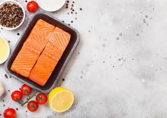 Plastic container with fresh salmon slice with oil tomatoes and lemon on stone kitchen background. Space for text
