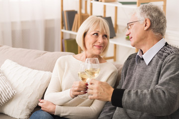 Senior couple clinking wine glasses and looking at each other