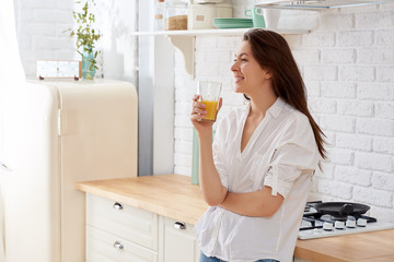 Portrait of a young woman drinking water in the kitchen at home