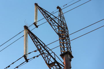 The fragment of the support of the air power line has wires, insulators, fittings and a lightning rod. Close-up, against the blue sky wires and high-voltage support line.