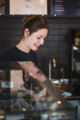 happy woman or waitress with cakes and tongs at cafe counter. small business, food, people and service concept, selective focus, noise effect. selective focus, noise effect