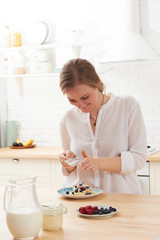 happy young woman preparing tasty snacks at the kitchen table in the morning light