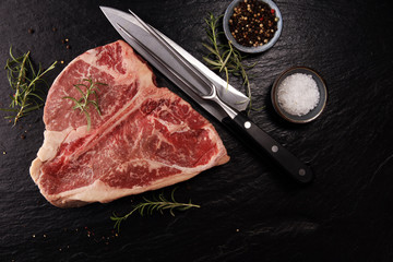 Raw T-bone steak on stone cutting board.