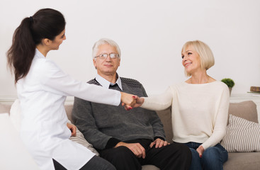 Senior couple welcoming doctor during home visit