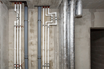 Pipes of heating and water supply system on the background of a concrete wall.