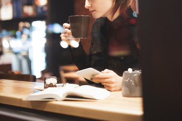 An attractive girl sits in front of a panoramic window at the cafe, drinking coffee and eating dessert. selective focus, noise effect