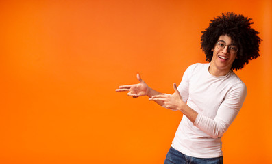 Stylish black man in glasses pointing away at empty space