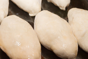 Freshly made pies lie on a baking sheet before cooking
