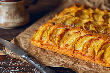 Homemade rustic apple pie on a wooden old vintage table. Dark background. Seasonal bakery concept.