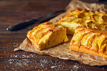 Homemade rustic apple pie on a wooden old vintage table. Dark background. Seasonal bakery concept.