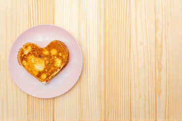 Heart shaped pancakes for romantic breakfast. Shrovetide (carnival) concept. On wooden background, top view