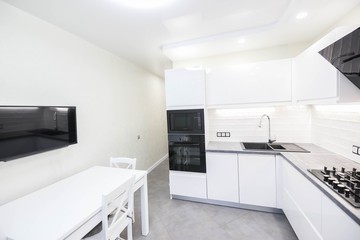 modern white kitchen interior with   LED backlight. Household appliances oven, gas stove, hood.