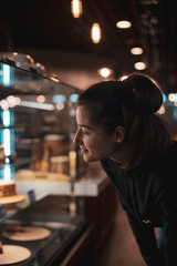 In pastry shop girl choose colorful cake and pie from showcase. selective focus, noise effect