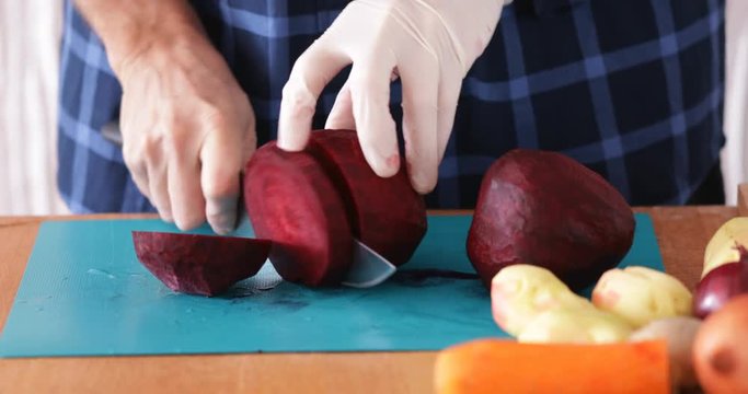 Cooking at home, Man chopping beetroot using sharp knife, close-up, steadicam