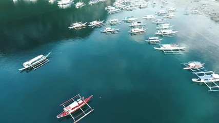 Aerial drone view of boats anchored in the bay with clear and turquoise water. Boat and yacht in the tropical lagoon. Tropical landscape. El Nido, Palawan island, Philippines.