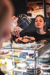happy woman or waitress with cakes and tongs at cafe counter. small business, food, people and service concept, selective focus, noise effect