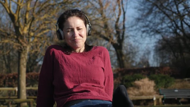 Happy Woman  dancing On The Park, with headphones and smartphone Listening to music with joy. Woman enjoying the sun and feeling the freedom. 4K