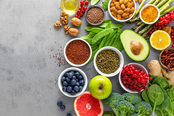 Healthy food background, spinach, quinoa, apple, blueberry, asparagus, turmeric, red currant, broccoli, mung bean, walnuts, grapefruit, ginger, avocado, almond, lemon, green peas and goji, top view