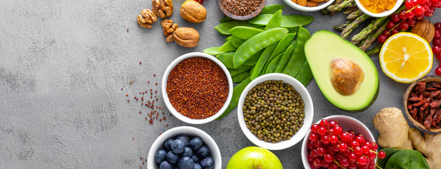 Healthy food background, spinach, quinoa, apple, blueberry, asparagus, turmeric, red currant, broccoli, mung bean, walnuts, grapefruit, ginger, avocado, almond, lemon  and green peas, top view, banner