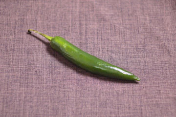 Green burning pepper on table