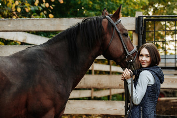 Portrait of smiling female jockey standing by horse in stable
