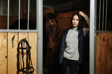 Portrait of smiling female jockey standing by horse in stable