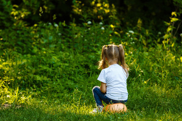 Fototapeta premium The smiling little cute baby girl is playing with small soccer ball for children on green grass playing field