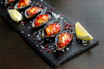 Fresh oysters are laid out on black slate, coarse salt is sprinkled around. Seafood.