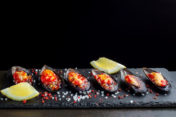 Six oysters. Fresh oysters are laid out on black slate, coarse salt is sprinkled around. Seafood.