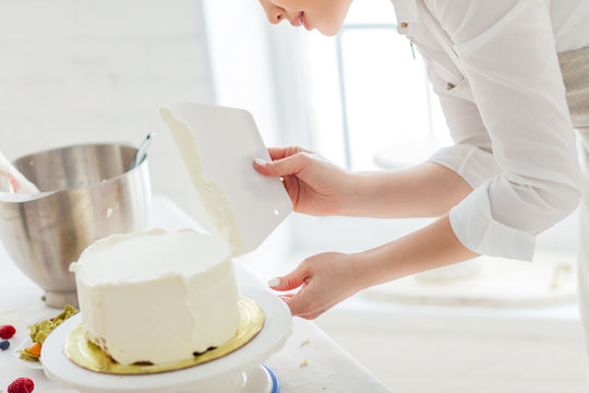 housewife smoothing the edges of cake, close up side view photo