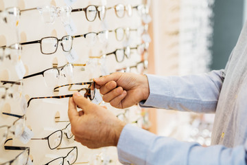 closeup of man choosing glasses in optic store. detail of hands