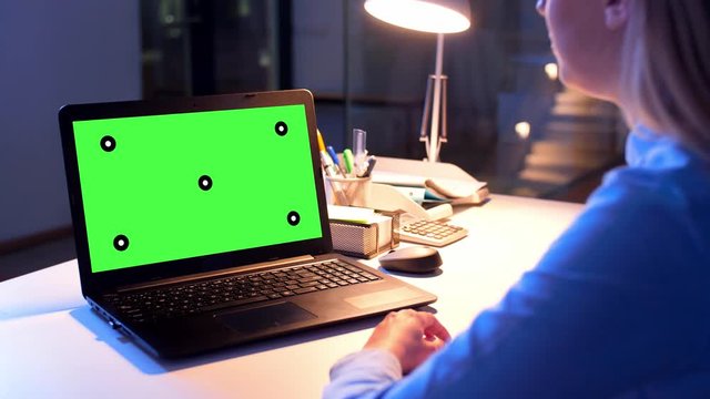 business, deadline and technology concept - businesswoman with chroma key green screen on laptop computer having video call at dark night office