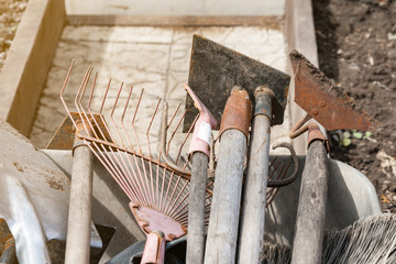 old dirty garden shovels, rakes, hoes in a trolley