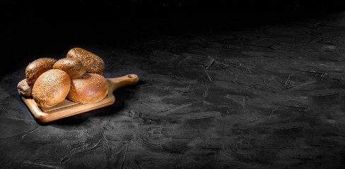Freshly buns with sesame seeds for hamburger on dark background. Free space for text