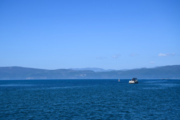 Tourist boat is sailing on Ohrid Lake. Mountain background. Ohrid, Macedonia.