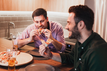 Two guys enjoying eating pizza at home