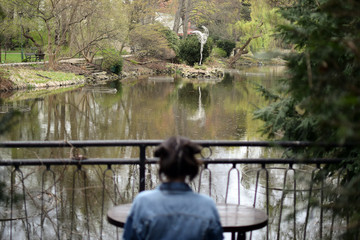 Young woman is looking at the lake in park.