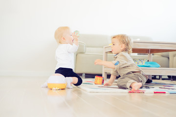 Cute little girl and boy playing with toys at home