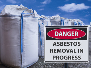 sign asbestos removal in progress and a stack of big bags of asbestos.