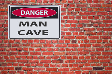 sign danger man cave on red brick wal