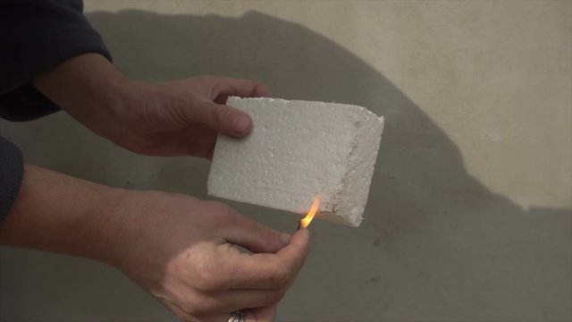 man burns foam polystyrene from a match