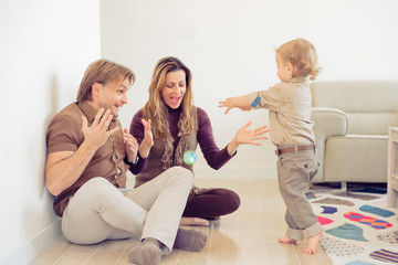 Happy family sitting on floor with their little baby. Family spending time at home with their son.