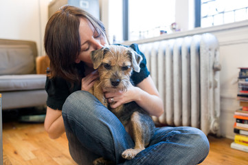 Woman kisses her pet border terrier