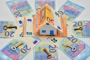 Casa de billetes de euro rodeada de billetes y llaves