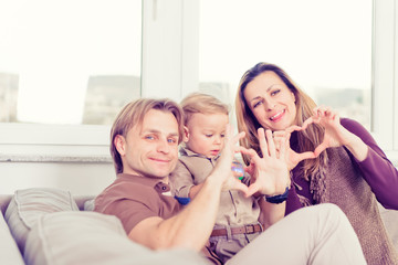 Portrait of happy family sitting on the sofa and smiling. Heart shape love.