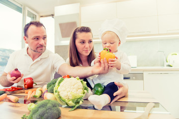 Happy parents sitting in the kitchen and prepares for cooking with their baby girl chef.