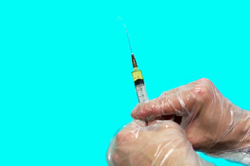 Gloved hands holding a syringe. Object isolated on blue background. Concept: vaccination, first...